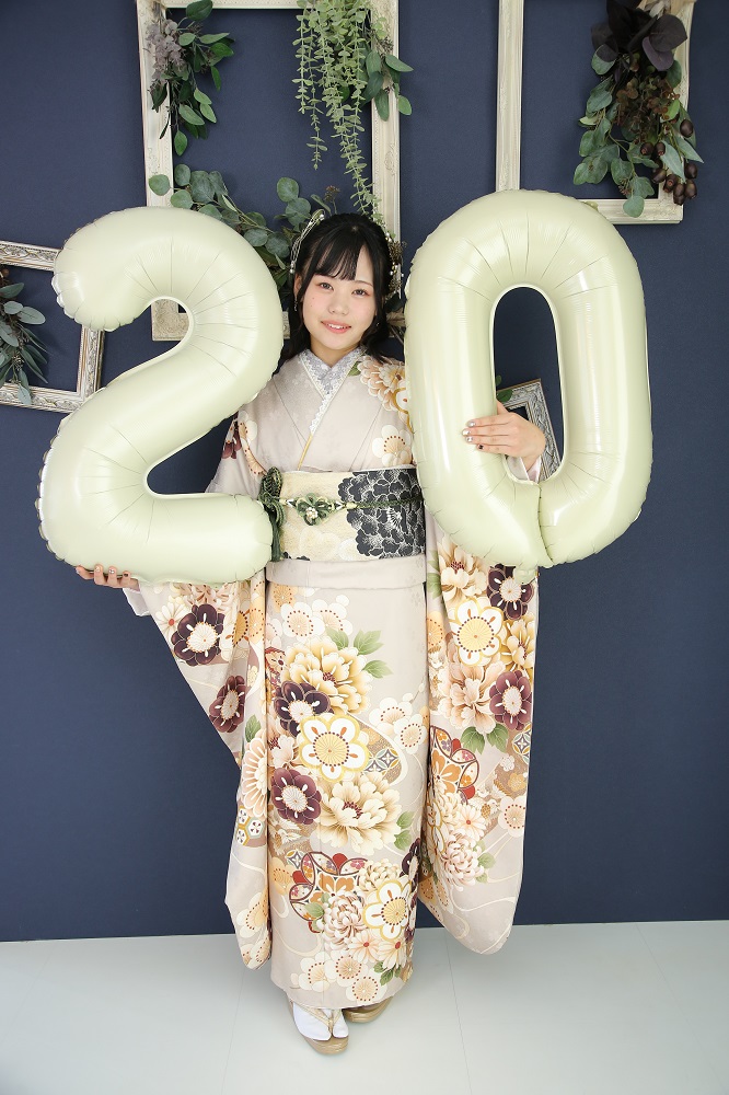 ベージュくすみカラー振袖を着て２０の大きな風船を持っている女性